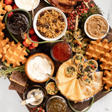 Sweet, Savory & Spicy Brunch Board featuring Blake Hill Naked Blueberry, Strawberry with Wild Rose, and Jalapeño & Lime jams with waffles, bacon, scones, granola, mini crepes, mini quiche, and seasonal garnish