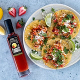 Fish tacos with strawberry slaw, Cotija cheese, cilantro, and lime wedges on corn tortillas