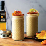 Not Your Mom's Piña Colada blended cocktail with a Sweet Smoked Chili Rub rim and Olivelle Pineapple Habanero White Barrel Aged Balsamic, garnished with maraschino cherries