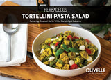 Herbaceous tortellini pasta salad with basil pesto, roasted asparagus, cherry tomatoes, and mozzarella balls