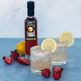 Strawberry lemonade gin fizz in a rocks glass with a frothy egg white top and lemon round garnish