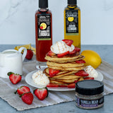Lemon ricotta pancakes topped with balsamic-marinated strawberries and whipped cream, made with Olivelle Strawberry Lemonade White Barrel Aged Balsamic and Sicilian Lemon Infused Olive Oil