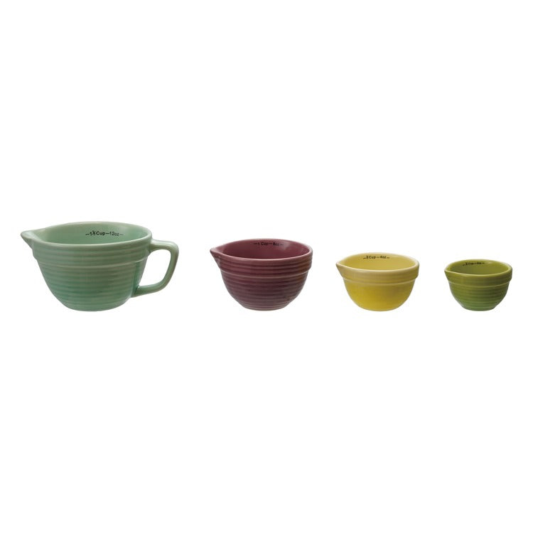 Set of four ceramic meauring cups  in different colors on a white background