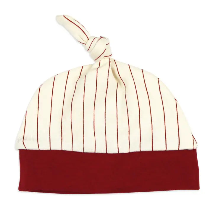 A baby knit hat with a cream-colored top half featuring thin red vertical stripes, a solid dark red bottom cuff, and a matching knotted top, shown on a plain white background.