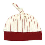 A baby knit hat with a cream-colored top half featuring thin red vertical stripes, a solid dark red bottom cuff, and a matching knotted top, shown on a plain white background.