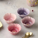 Set of four pink ceramic bowls with floral design on a light surface.