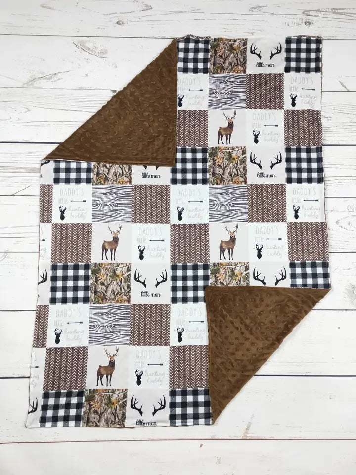 Patchwork blanket with deer and arrow patterns on a wooden surface
