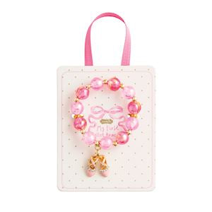 Pink beaded bracelet with a gold charm on a white background