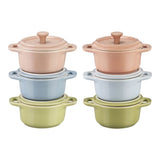 Set of four small ceramic pots with lids in pastel colors on a white background