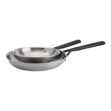 Two nested stainless steel sauté pans with black handles, shown on a plain white background.