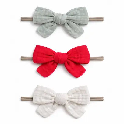 Three fabric bow hair clips in sage green, bright red, and off-white, arranged vertically on a plain white background.