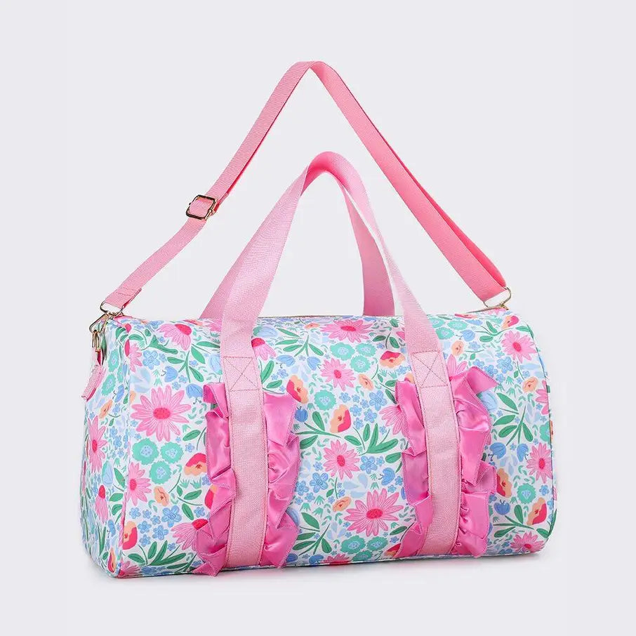 A duffel bag with a light blue floral print, pink handles and shoulder strap, and pink ruffle trim along the front.