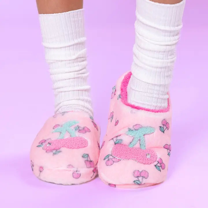 Pink slippers with cartoon characters worn with white socks on a purple background