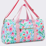 A duffle bag with a light blue and white floral print, pink handles and shoulder strap, and gold-tone hardware, shown on a light gray background.
