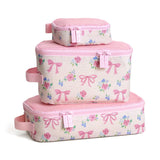 Set of three pink floral and bow-patterned cosmetic bags on a white background
