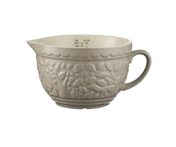 Beige ceramic mixing bowl with embossed design on a white background
