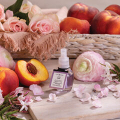 Skincare bottle with peaches and flowers on a wooden surface