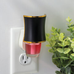 Wall-mounted night light with black shade and red interior, next to a plant on a white wall.