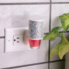 Decorative night light with rhinestone cover plugged into a wall socket.