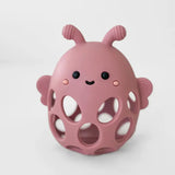 Pink silicone teething ball with a cute face on a white background