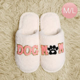 White slippers with 'DOG MOM' text on a textured beige surface