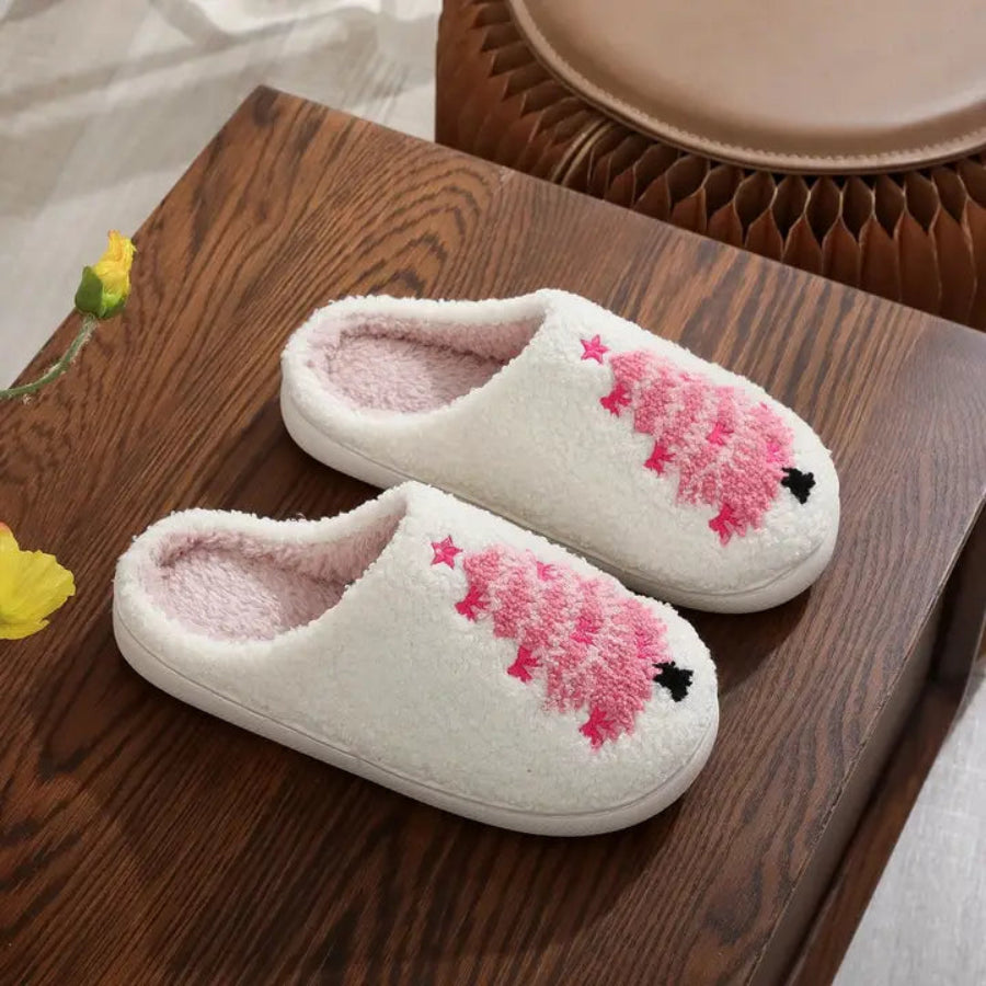 Pair of white slippers with pink tree design on a wooden surface