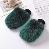 Pair of green fur slippers on a white surface with a blurred background