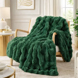 A plush, deep green textured throw blanket draped over a light wood armchair in a bright, modern living room setting.