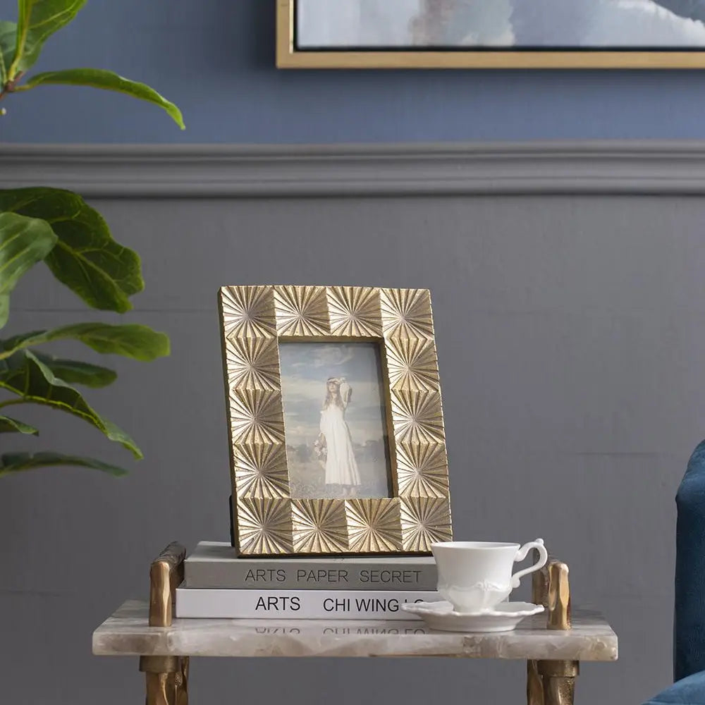 Decorative photo frame on a small table with a cup and saucer, against a gray wall.