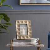 Decorative photo frame on a small table with a cup and saucer, against a gray wall.