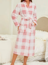 Person wearing a pink and white checkered robe in a bedroom setting.