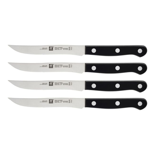 Set of four steak knives with black handles on a white background