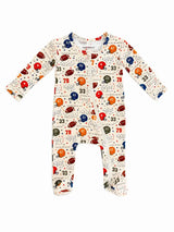 A baby long-sleeve footed sleeper with an all-over football-themed print on a cream background. The print features red, blue, and orange football helmets, footballs, numbers, and small stars.