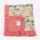 Floral-patterned blanket with pink ruffled edges on a white background