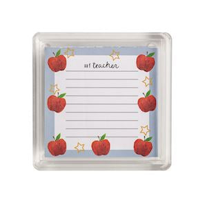 A square clear plastic case containing a lined notepad printed with red apples, small gold stars, and the words 'my teacher' at the top.