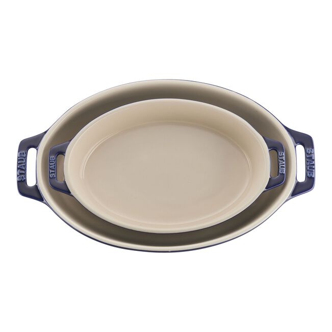 Oval ceramic baking dish with blue handles on a white background