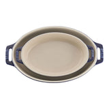 Oval ceramic baking dish with blue handles on a white background