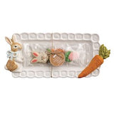 Decorative tray with rabbit figurine, carrot, and other Easter-themed items on a white background