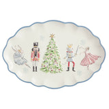 An oval ceramic serving platter with a scalloped edge, featuring a festive holiday illustration of a nutcracker, a princess, a prince, and a ballerina around a decorated Christmas tree on an off-white background with a blue rim.