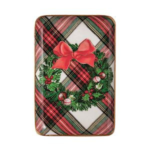 A rectangular holiday-themed product, likely a mat or cover, featuring a red and green plaid pattern with a central green wreath, red bow, and small red berries, shown on a plain white background.