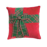A square red decorative pillow featuring a green and red plaid patterned band wrapped around the center like gift wrapping, tied into a bow, on a plain white background.