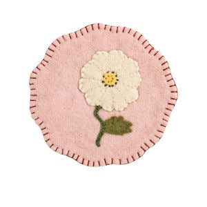 Round pink felt coaster with a white flower design on a white background