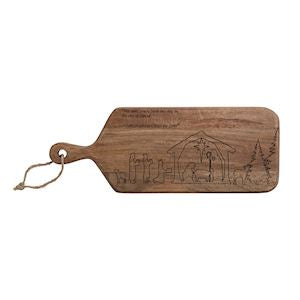 A rectangular wooden serving board with rounded corners, a hanging loop, and an engraved nativity scene on the front, shown on a plain white background.