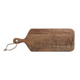 A rectangular wooden serving board with rounded corners, a hanging loop, and an engraved nativity scene on the front, shown on a plain white background.