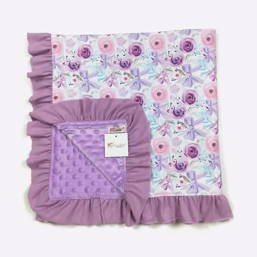 Purple floral and polka dot baby blanket with a visible brand tag on a white background