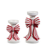 Two white ceramic candle holders with large red and white striped bows, shown on a plain white background.