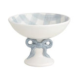 Decorative ceramic bowl with blue and white checkered interior and bow design on stand.