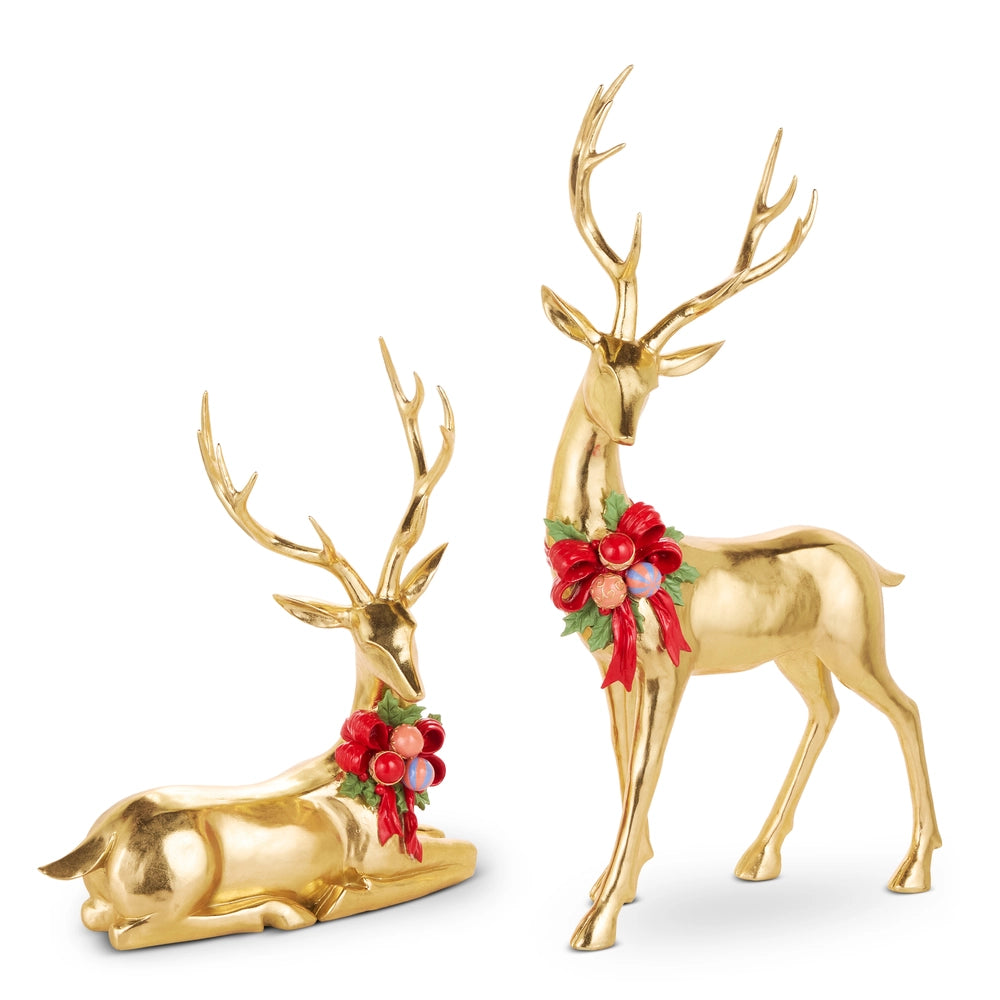 Gold deer figurines with red bows and greenery on a white background