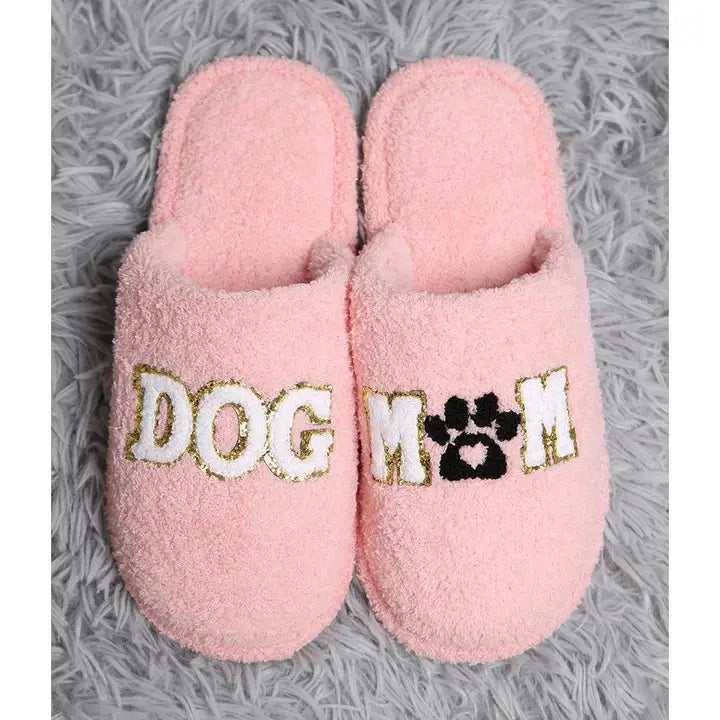 Pink slippers with 'DOG MOM' text on a gray textured background