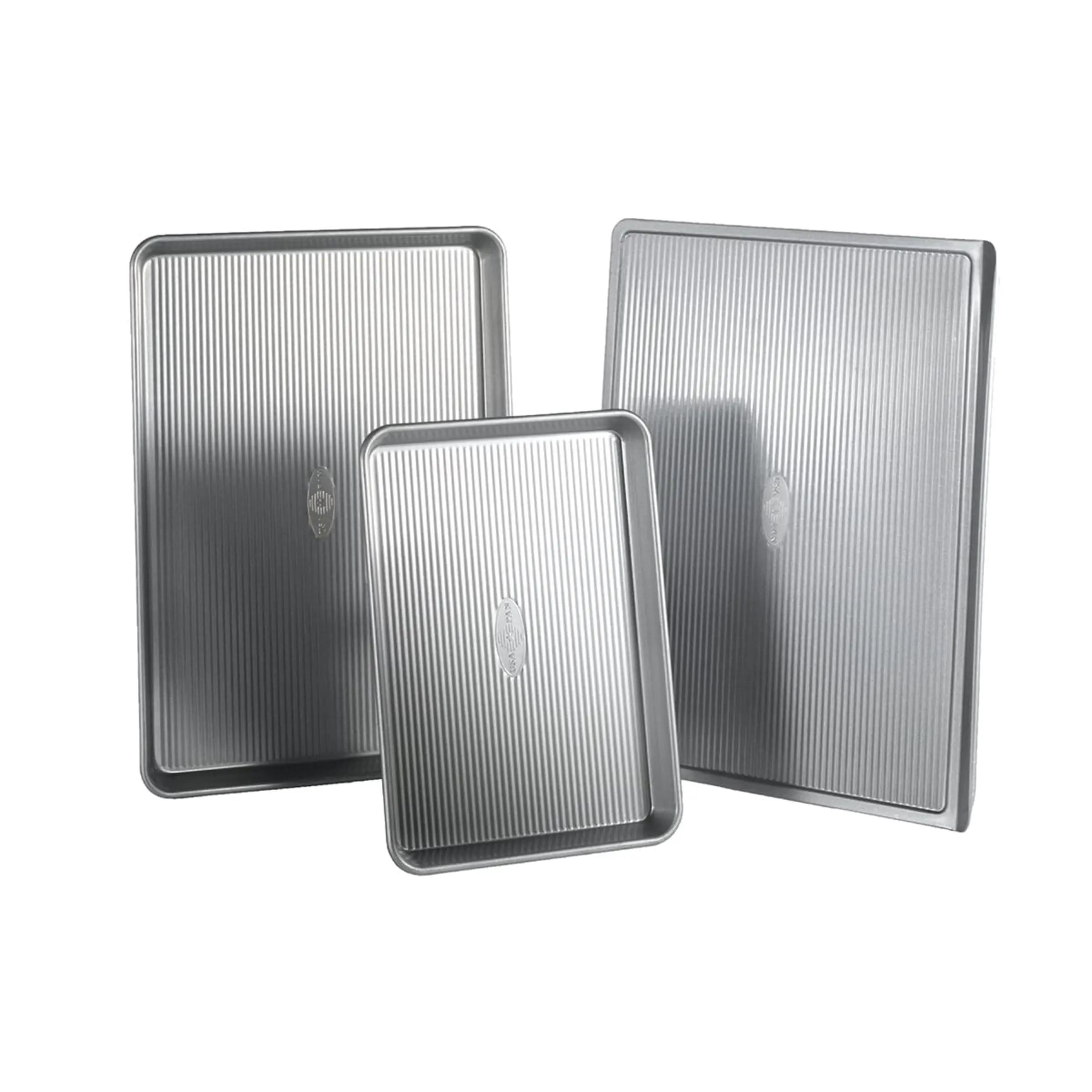 Three metal baking trays with ribbed surface on a white background
